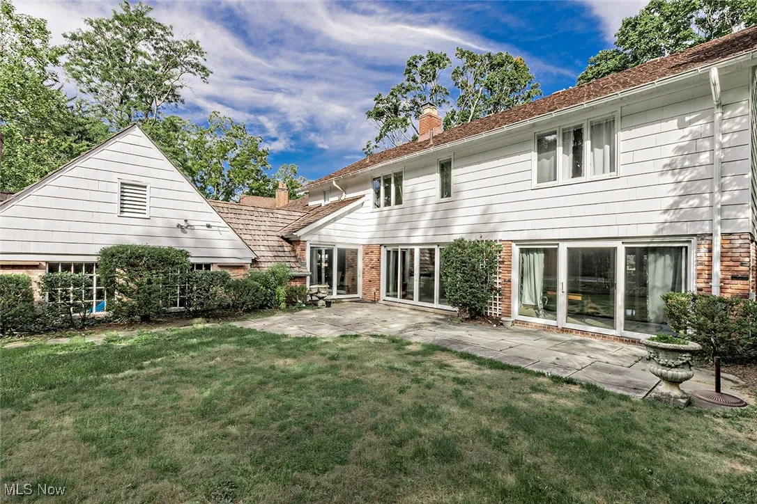Rear view of house with a chimney, a yard, a patio, and brick siding