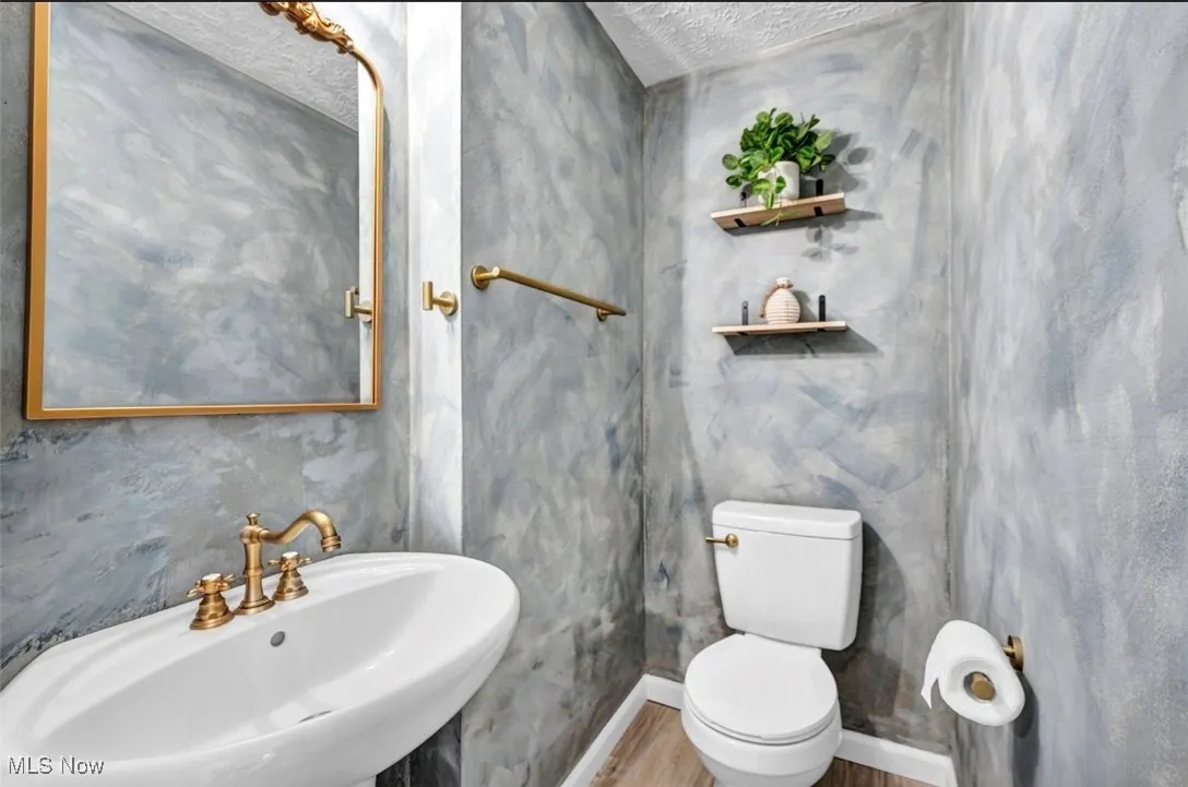 Half bath featuring a textured ceiling and wood finished floors