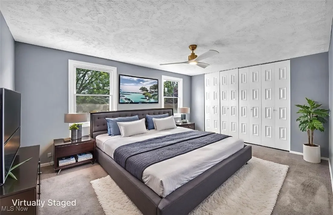 Carpeted bedroom with a closet, a ceiling fan, and a textured ceiling