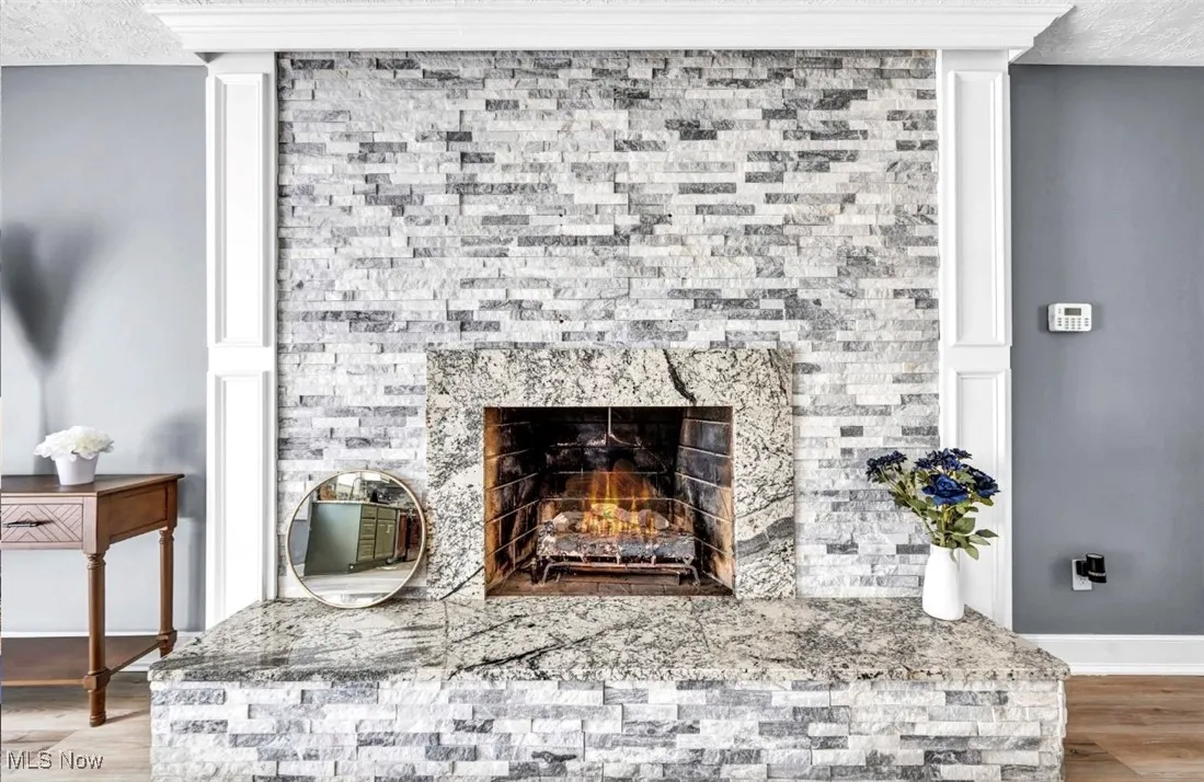 Detailed view of wood finished floors, a textured ceiling, and a lit fireplace