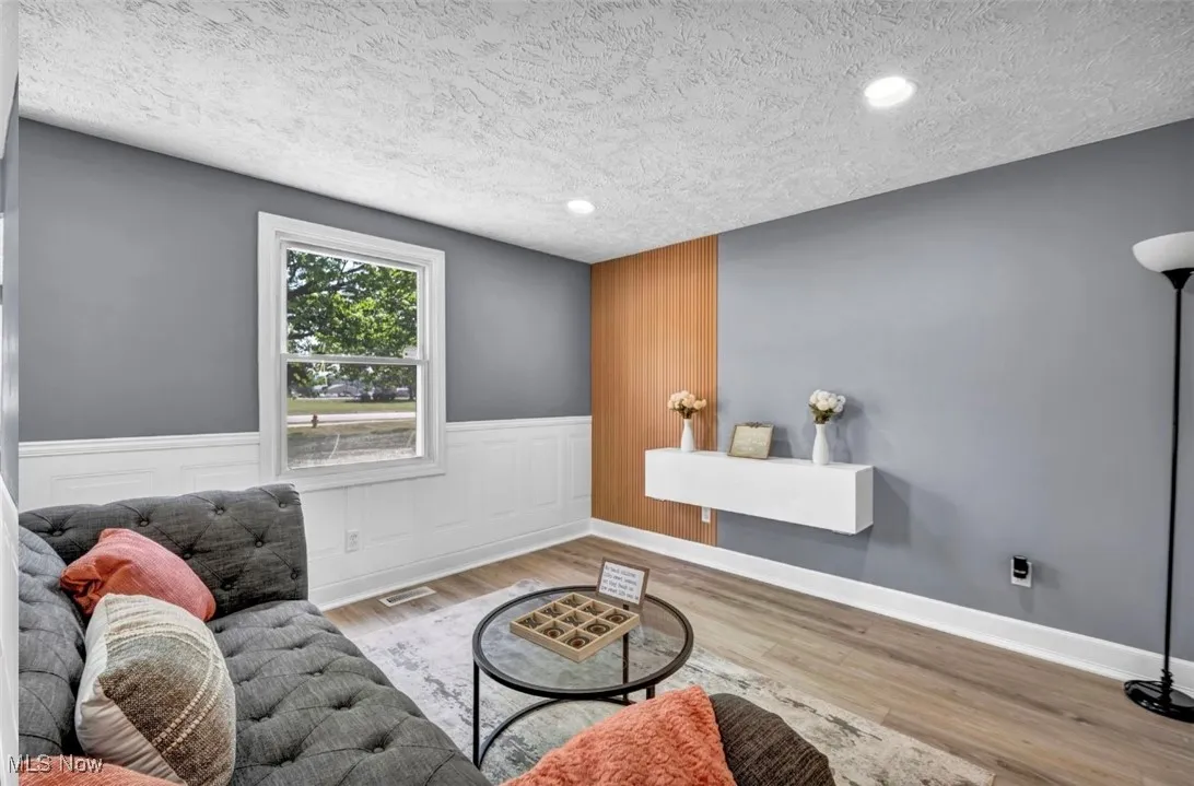 Living room featuring wood finished floors, wainscoting, a textured ceiling, and recessed lighting