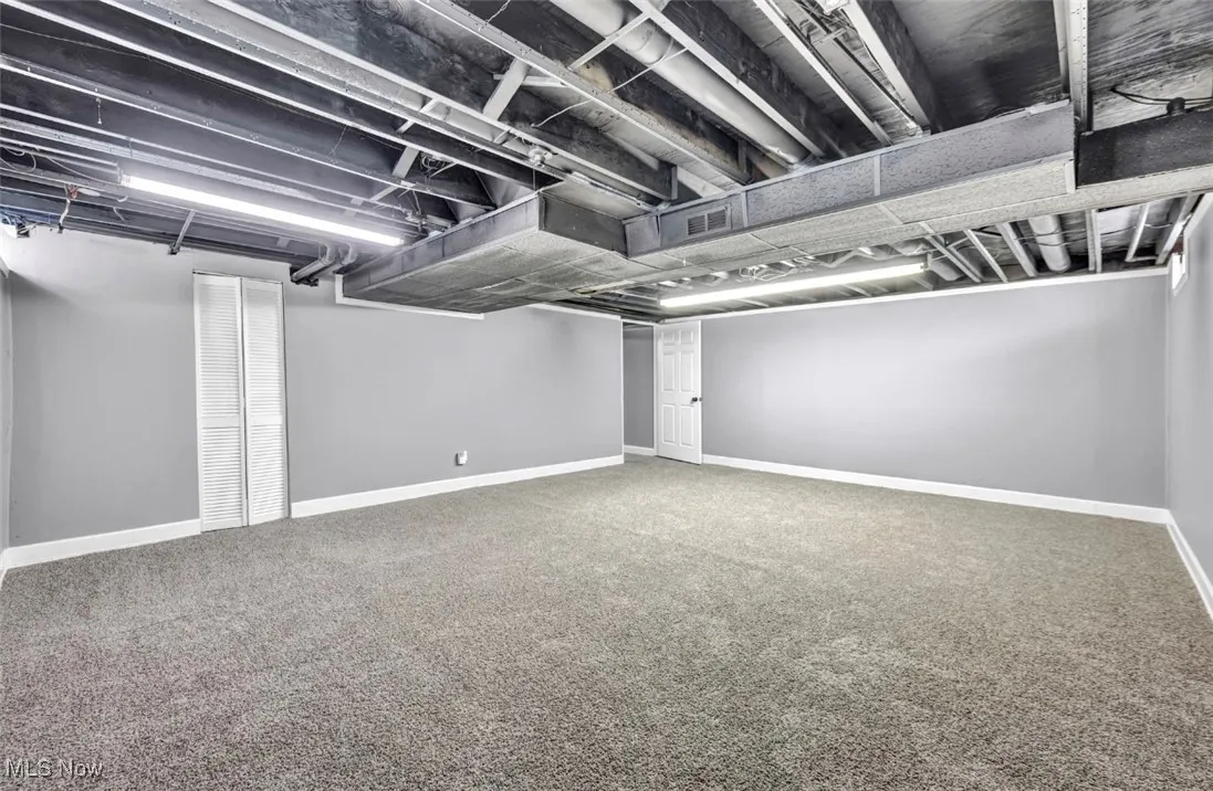 Finished below grade area featuring baseboards and light carpet