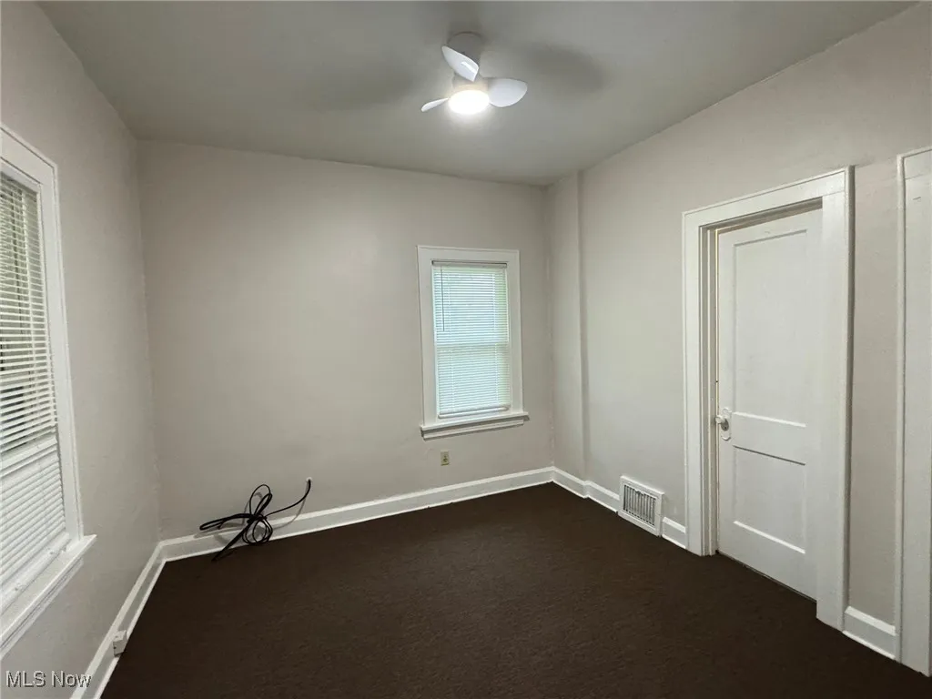Spare room with baseboards and dark carpet