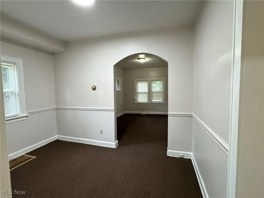 Empty room with arched walkways and dark carpet