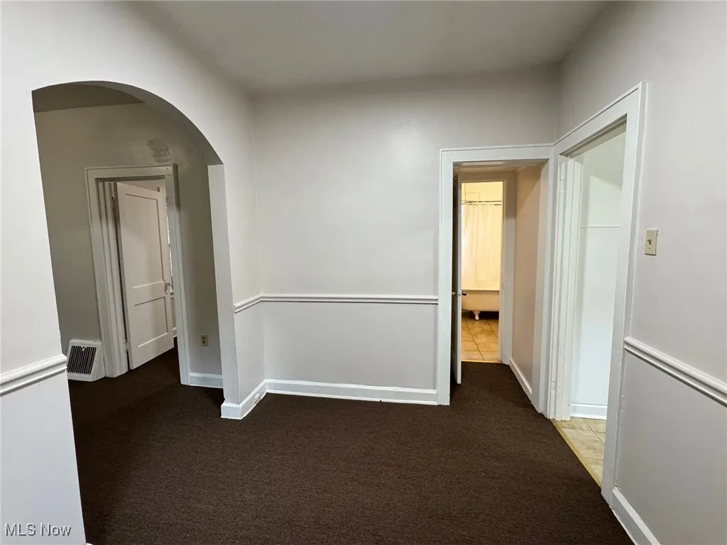 Hall featuring dark colored carpet and arched walkways