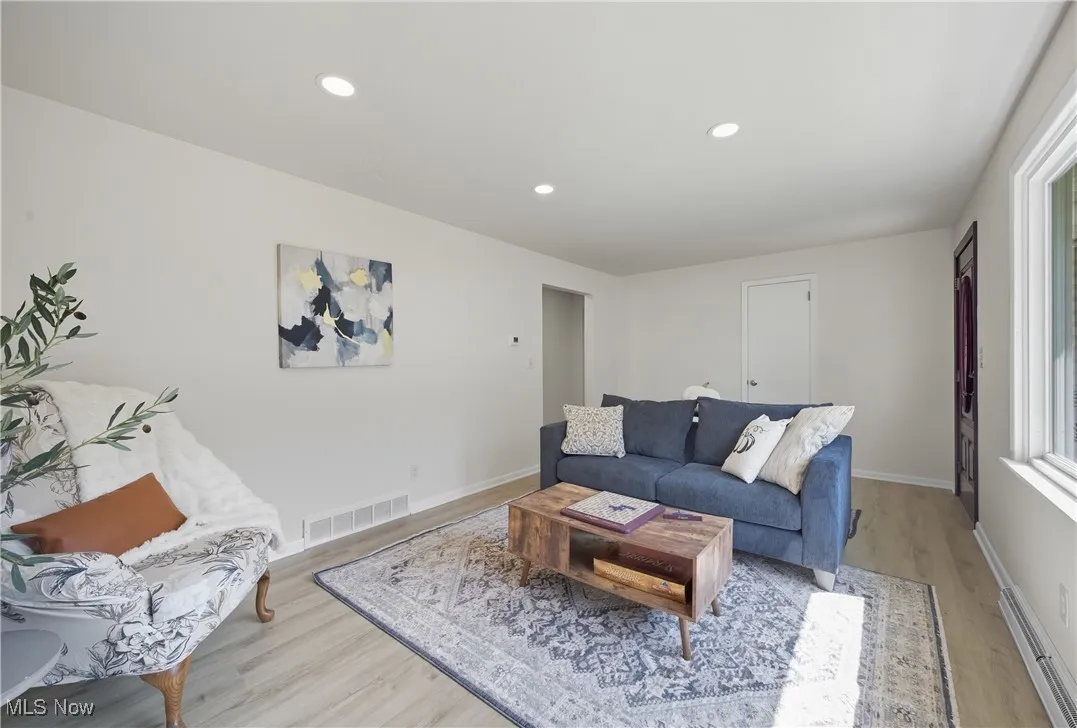 Living room with recessed lighting, a baseboard radiator, and light wood-type flooring