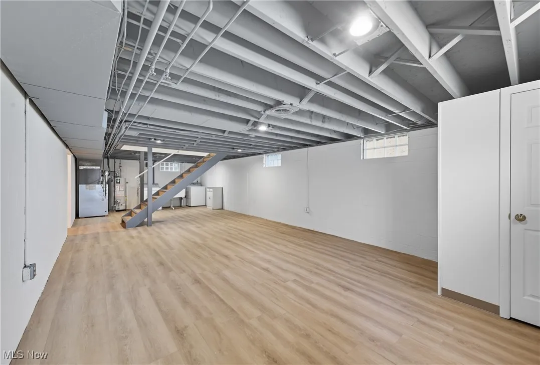 Basement with stairs, light wood-type flooring, washer / dryer, and water heater