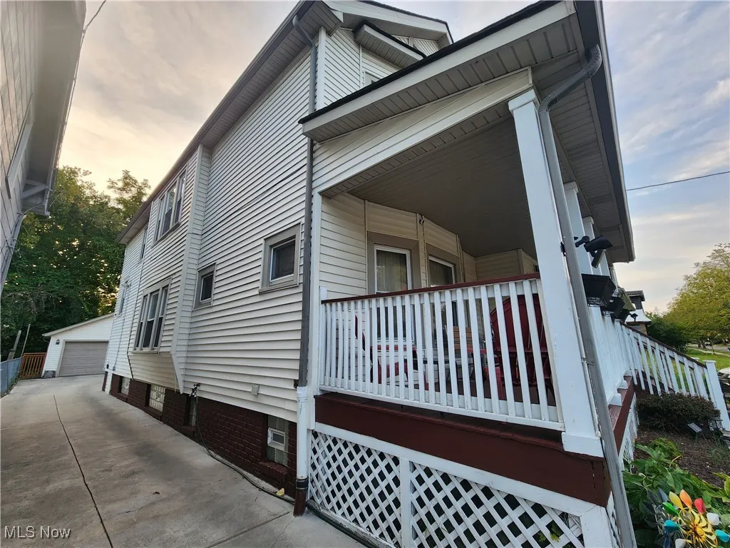 Property exterior at dusk with a garage, an outbuilding, and covered porch