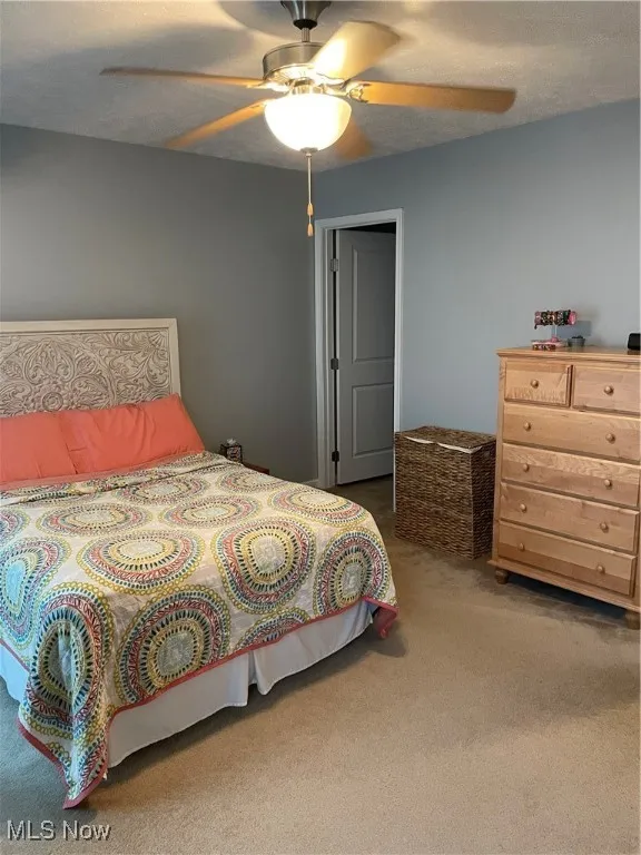 Bedroom featuring carpet, ceiling fan, and a textured ceiling