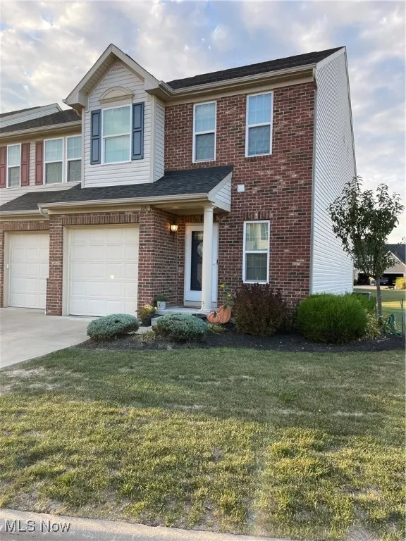 Traditional-style house with a front lawn, brick siding, concrete driveway, and a garage