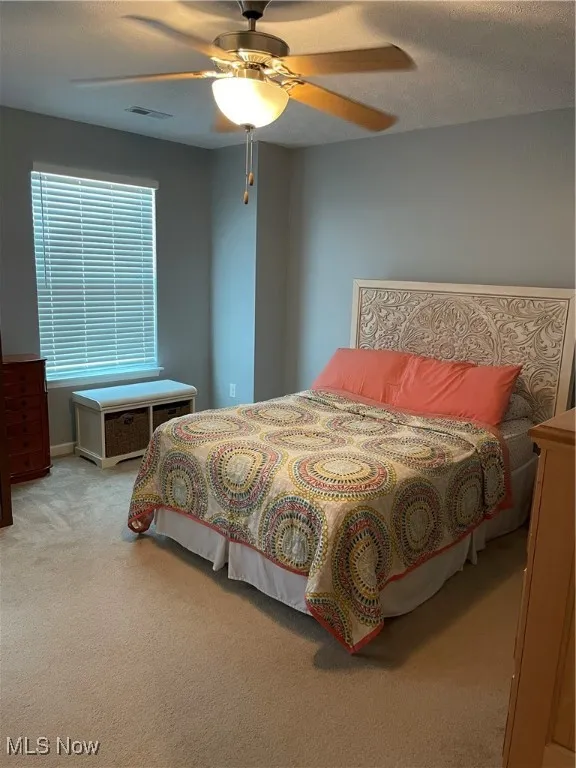 Bedroom with carpet floors, ceiling fan, and a textured ceiling
