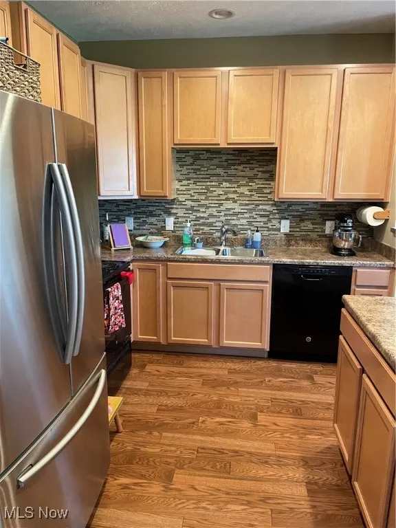 Kitchen featuring fridge, tasteful backsplash, dishwasher, range, and dark wood finished floors