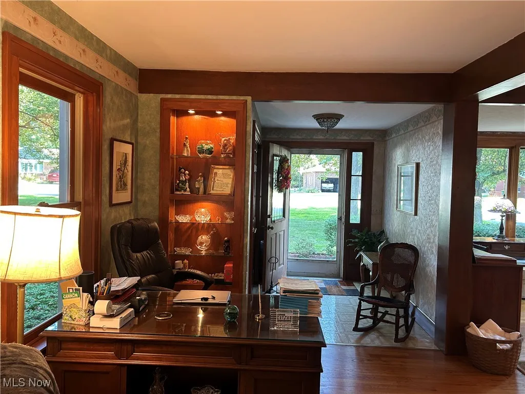 Home office featuring wallpapered walls and wood finished floors