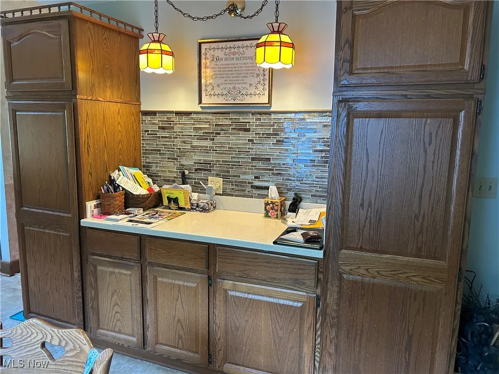 Kitchen featuring light countertops, decorative light fixtures, and brown cabinets
