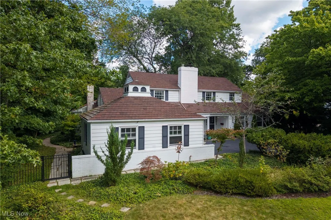 View of front of house featuring a chimney and view of scattered trees