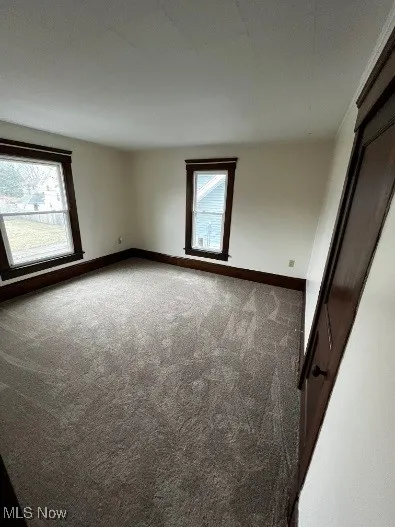 Empty room with carpet floors and baseboards