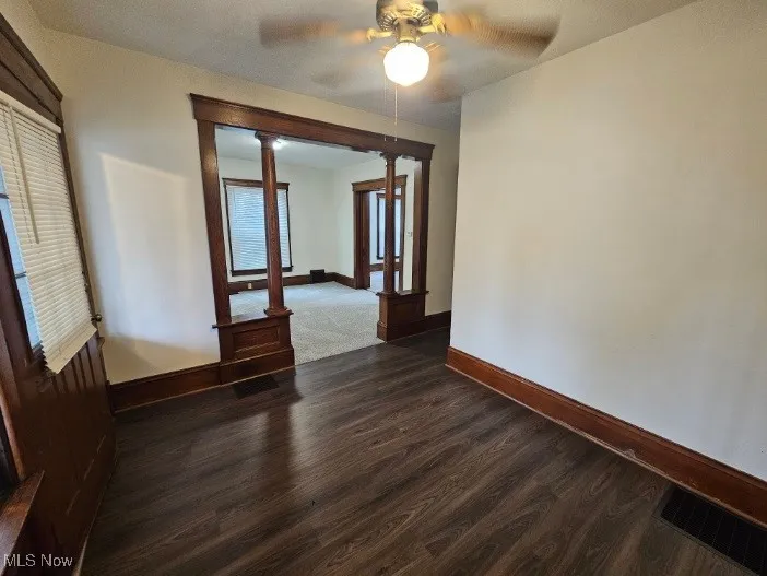 Unfurnished room with dark wood-style flooring and ceiling fan