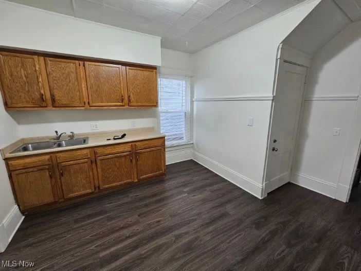 Kitchen featuring dark wood-type flooring, light countertops, brown cabinets, and lofted ceiling