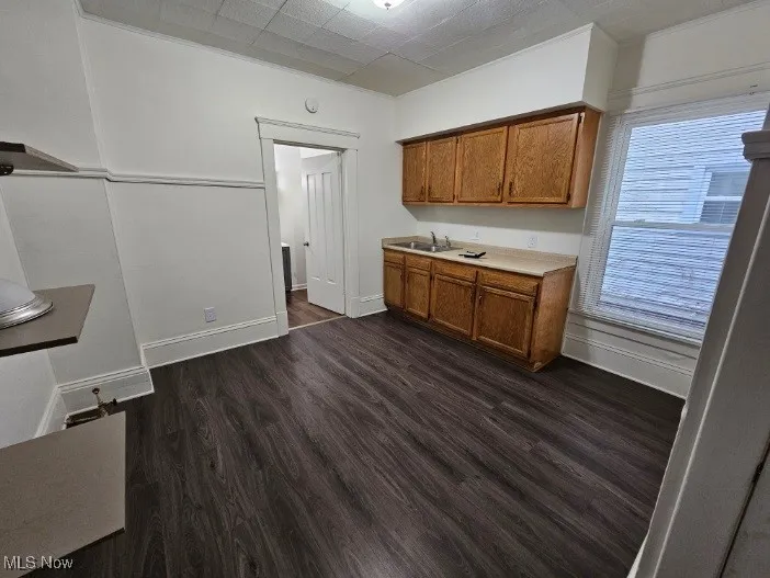 Kitchen featuring dark wood-type flooring, brown cabinets, and light countertops