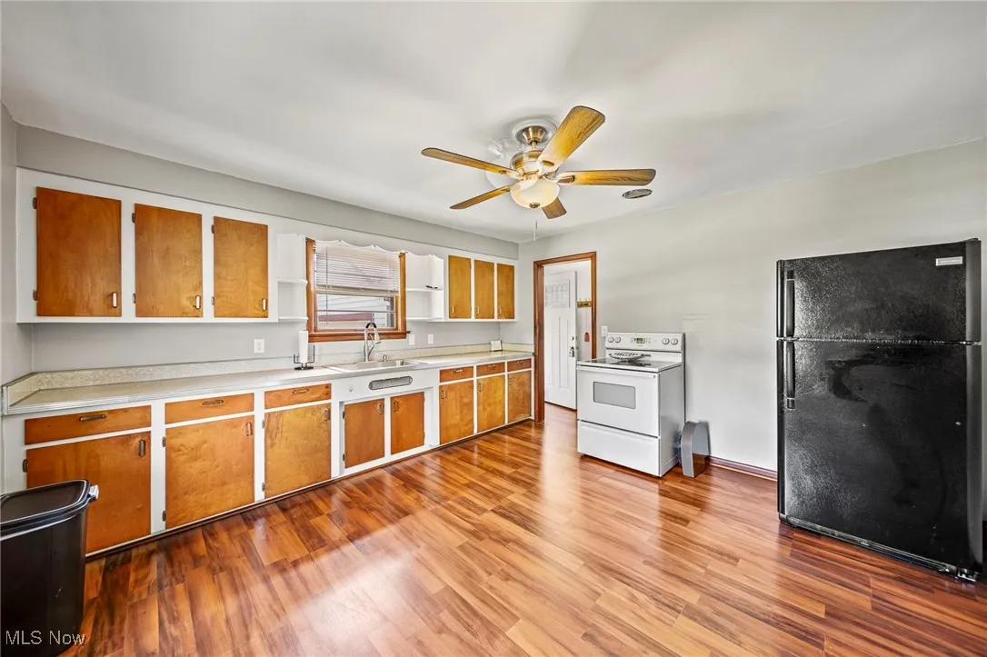Kitchen featuring light countertops, freestanding refrigerator, white range with electric cooktop, light wood-style flooring, and a ceiling fan