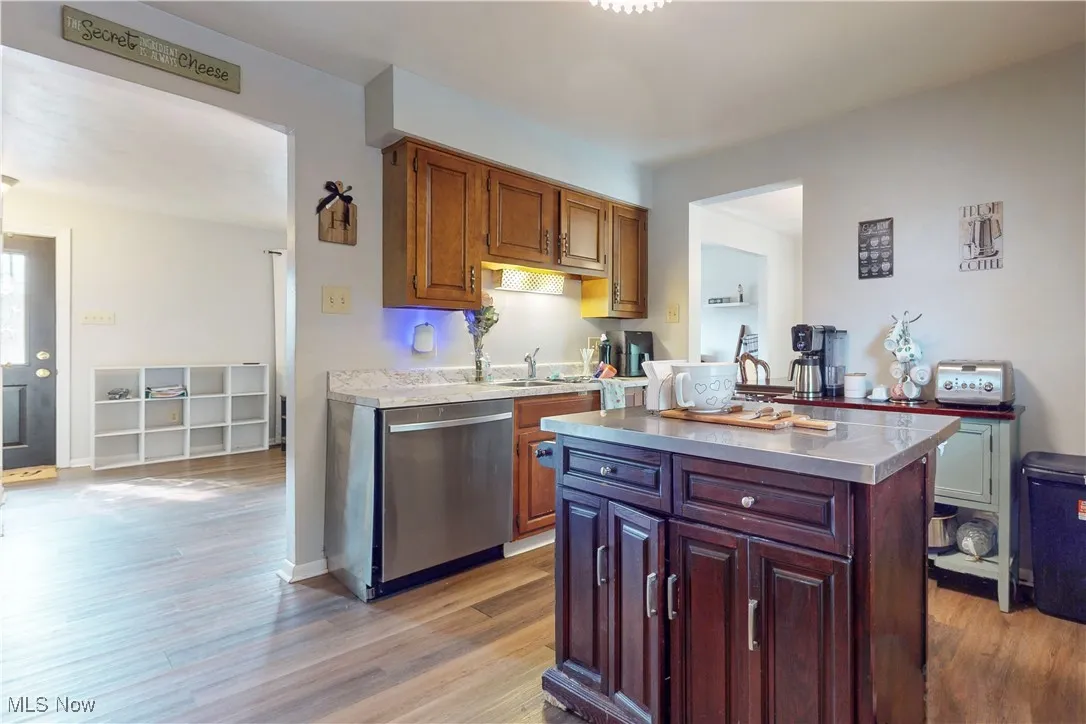 Kitchen featuring light countertops, dishwasher, light wood-type flooring, and a kitchen island