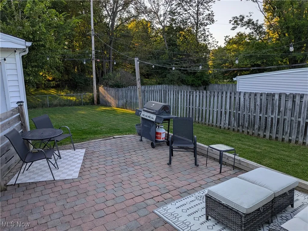 Fenced backyard featuring a patio area, grilling area, and view of wooded area