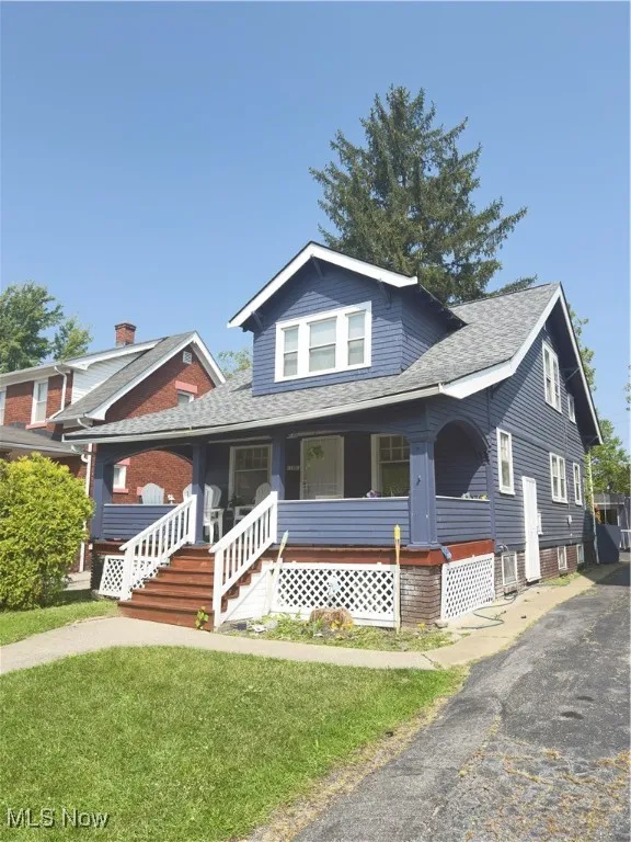 Bungalow with a porch, a shingled roof, and a front yard