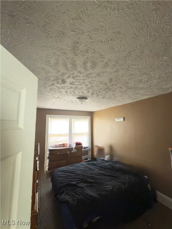 Bedroom with a textured ceiling and carpet flooring