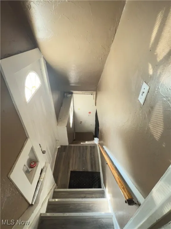 Stairway with a textured ceiling and wood finished floors