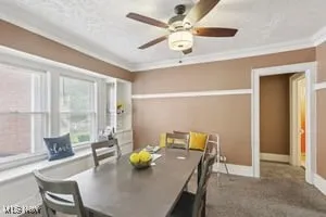 Dining space with ornamental molding, carpet, and a ceiling fan