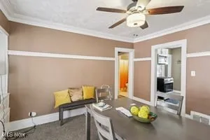 Carpeted dining room featuring ornamental molding and a ceiling fan