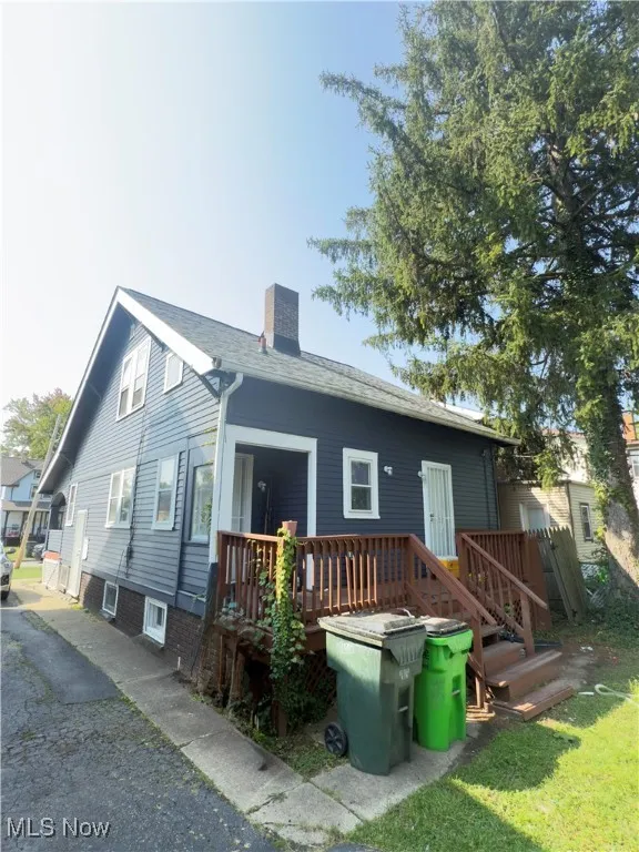 Back of house featuring a chimney and a wooden deck