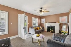 Living room featuring plenty of natural light, carpet, a fireplace, and a ceiling fan