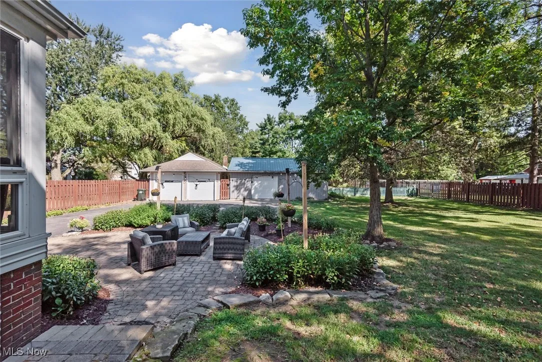 Fenced backyard featuring an outdoor hangout area, an outdoor structure, a patio, and view of wooded area