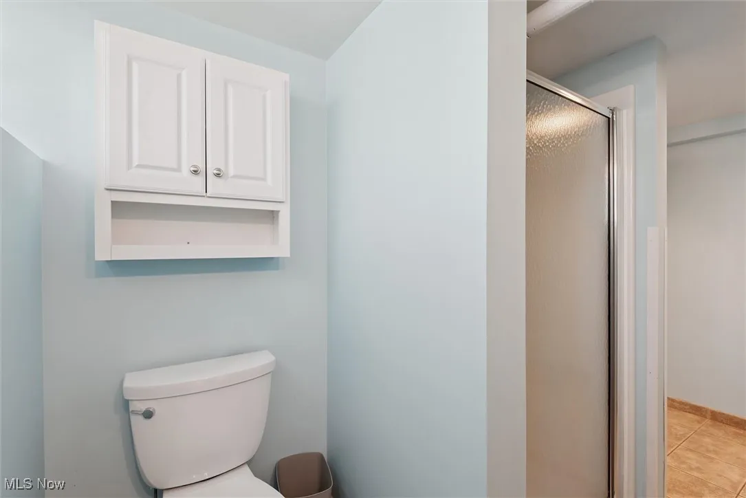 Bathroom with a shower stall and light tile patterned floors