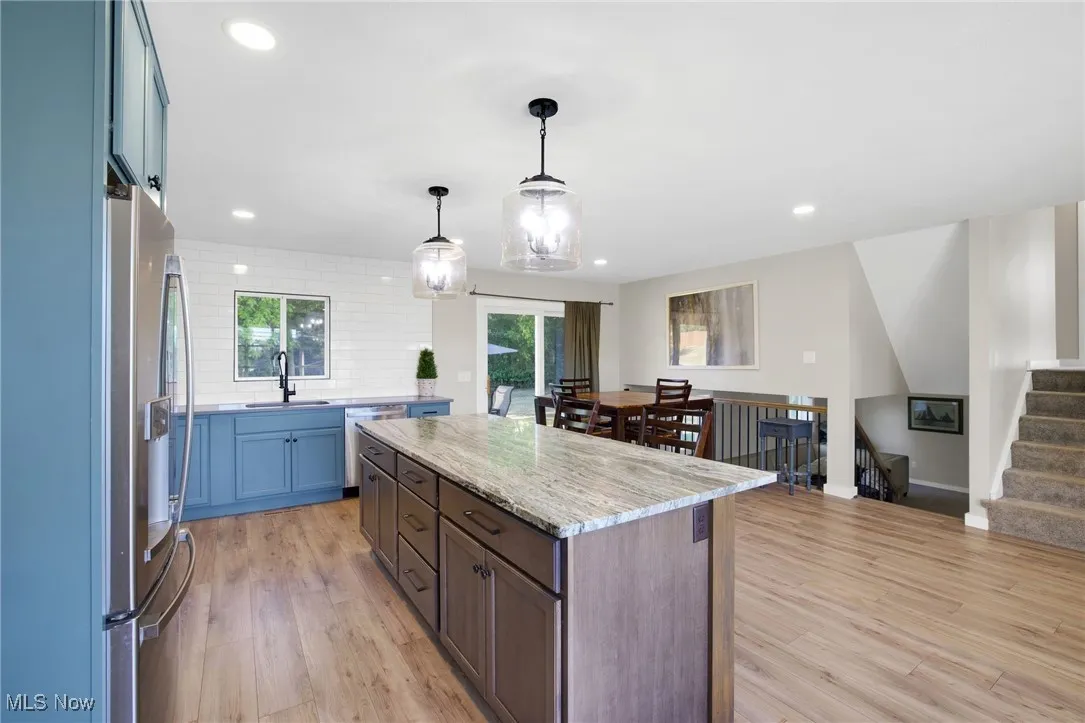 Kitchen with decorative backsplash, hanging light fixtures, light wood-style floors, a center island, and recessed lighting