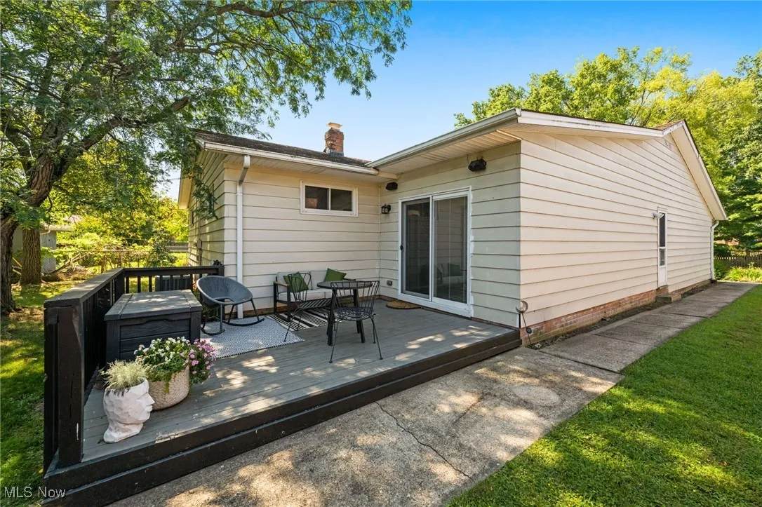 Back of house with a wooden deck, a chimney, and a lawn