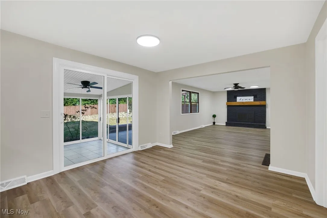 Unfurnished living room with a ceiling fan, a fireplace, and light wood-style flooring