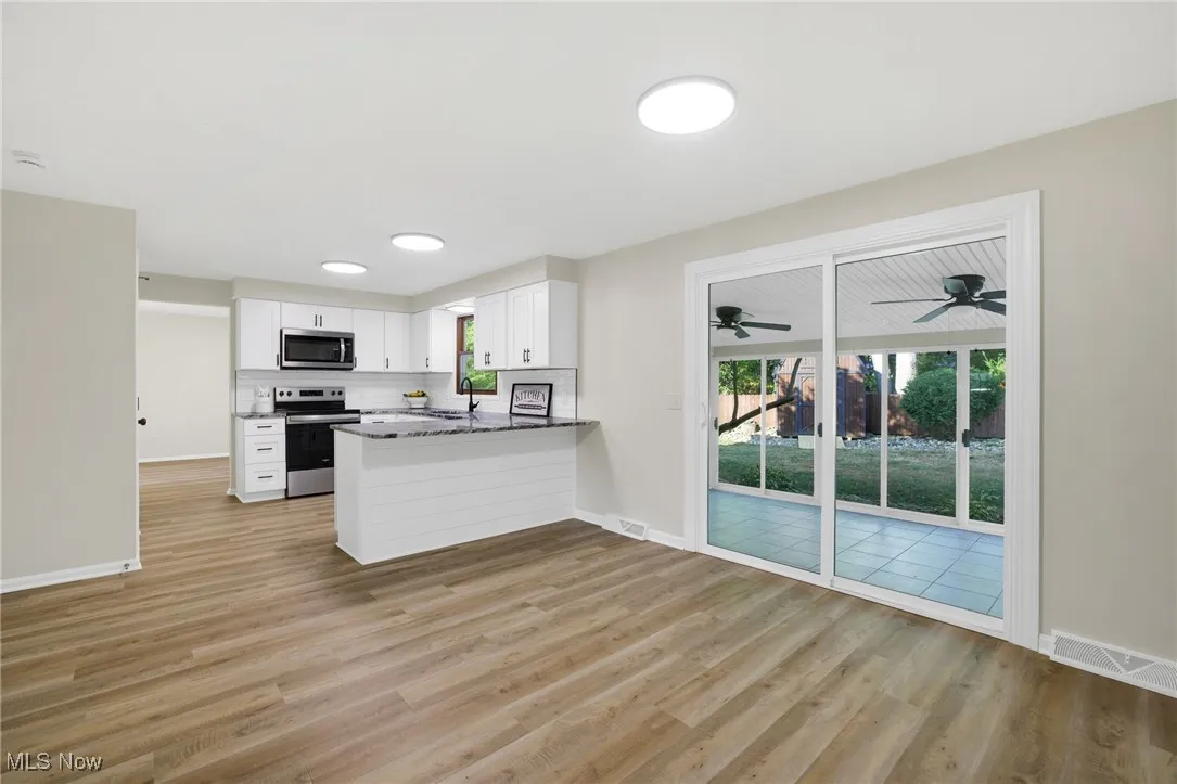Kitchen featuring white cabinetry, appliances with stainless steel finishes, light wood-style floors, and a peninsula