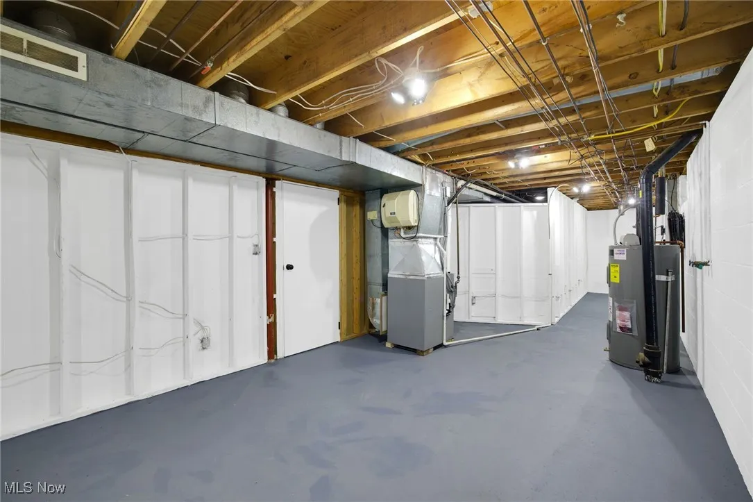 Unfinished below grade area with heating unit and electric water heater