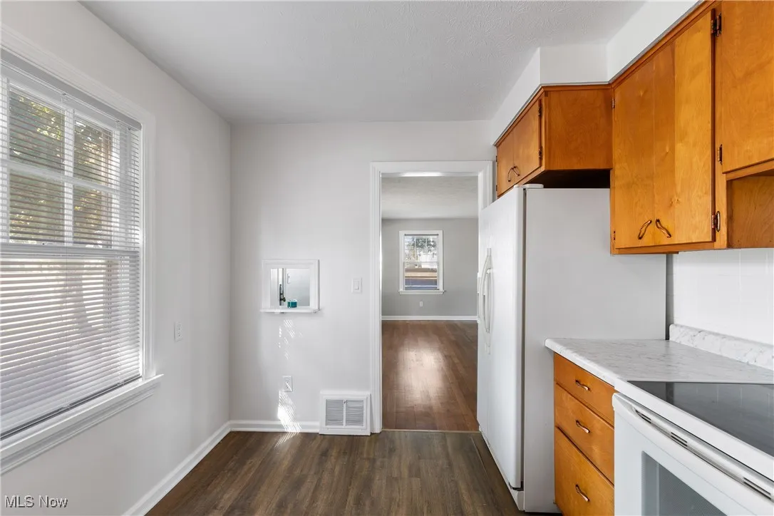 Kitchen with brown cabinetry, light countertops, dark wood-type flooring, and electric stove