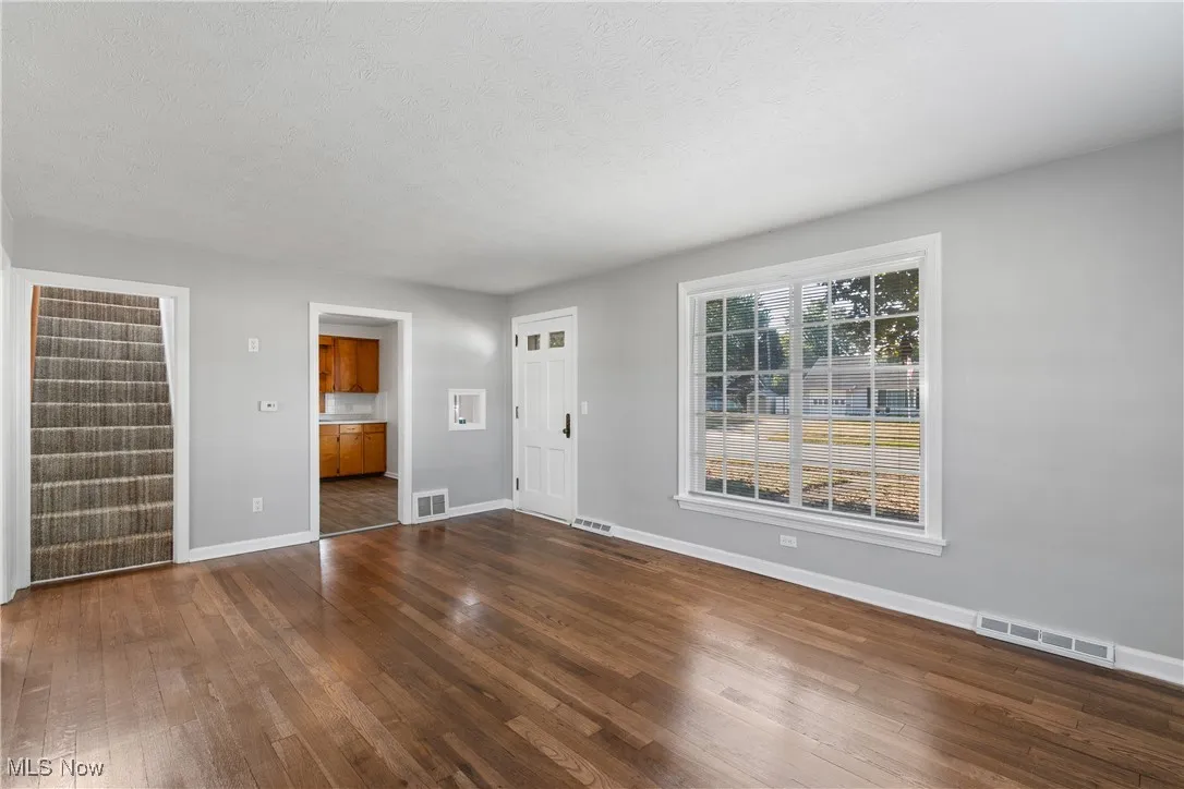 Unfurnished living room with dark wood-style flooring and a textured ceiling