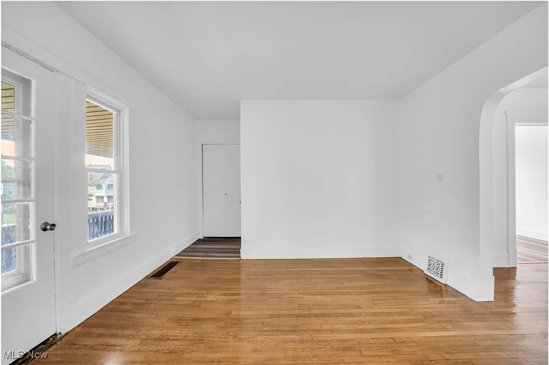 Unfurnished room featuring arched walkways and light wood-style floors