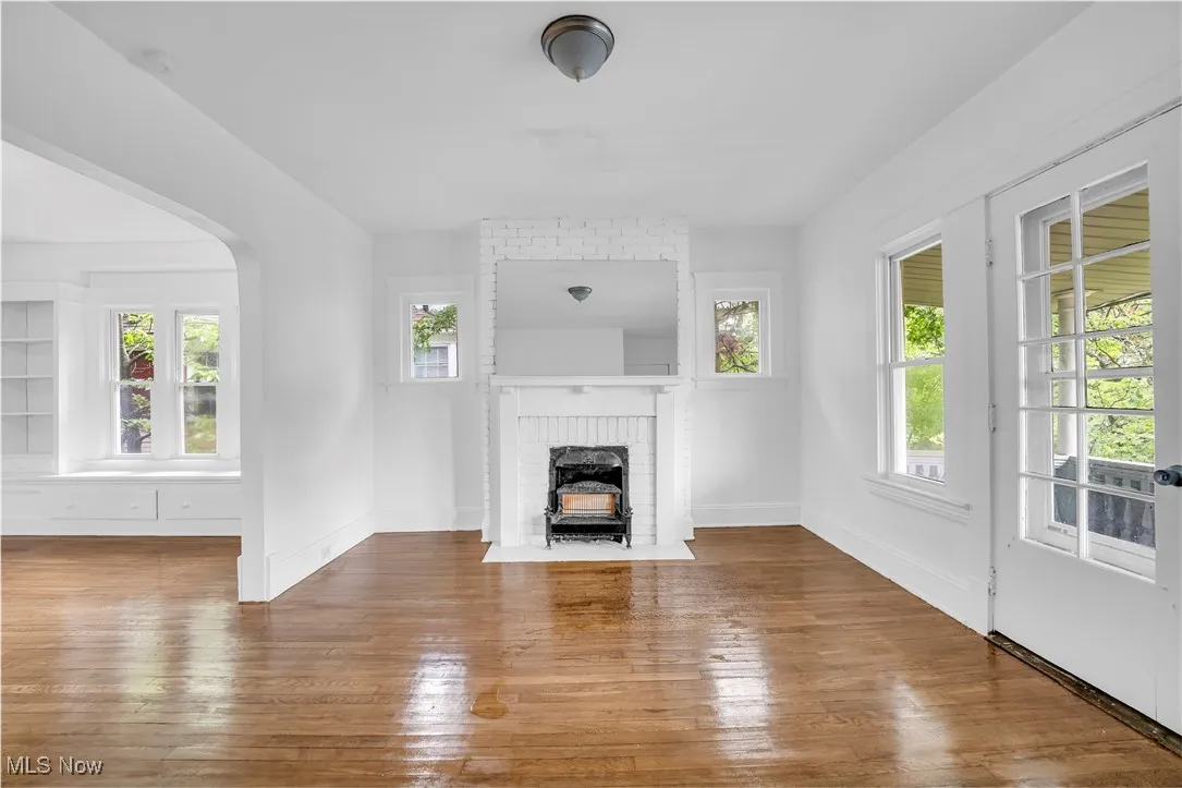 Unfurnished living room with arched walkways and hardwood / wood-style floors