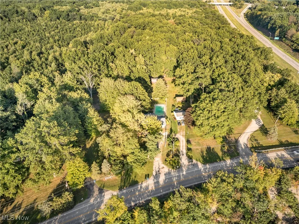 Aerial view of property and surrounding area featuring a heavily wooded area