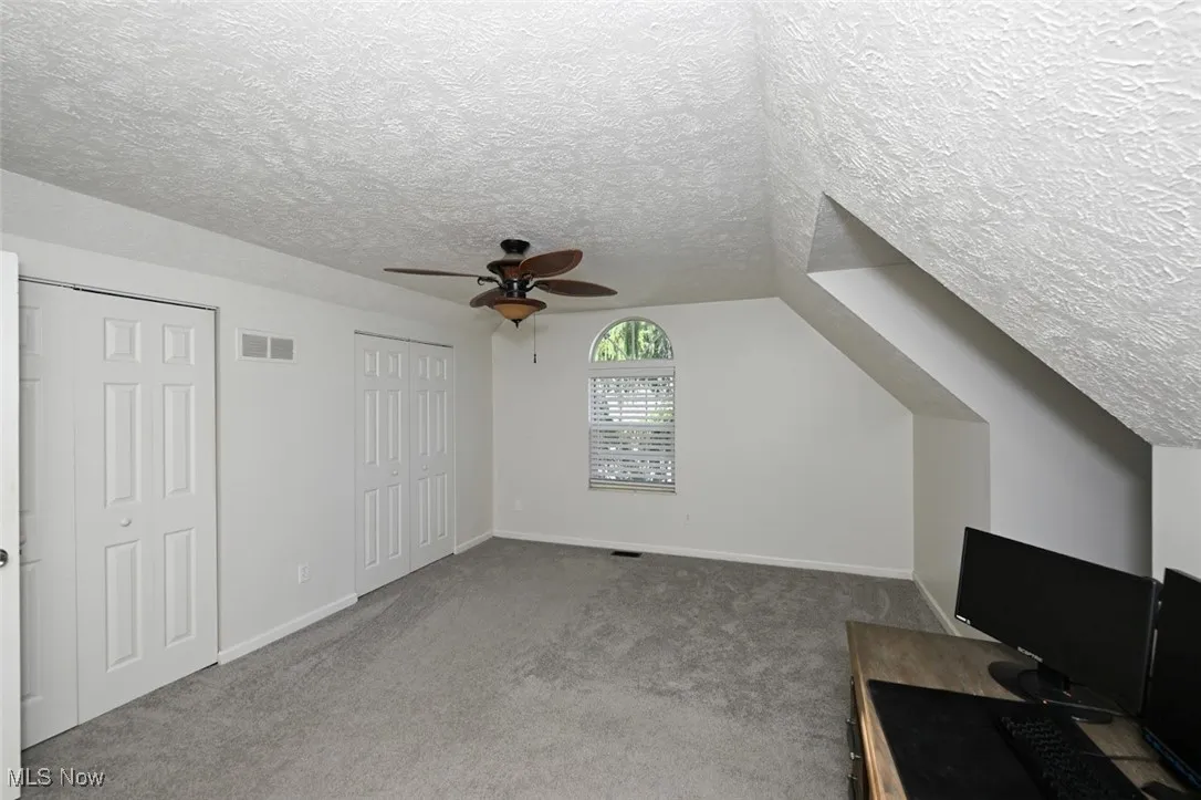 Bedroom featuring carpet flooring, a textured ceiling, ceiling fan, an office area, and vaulted ceiling