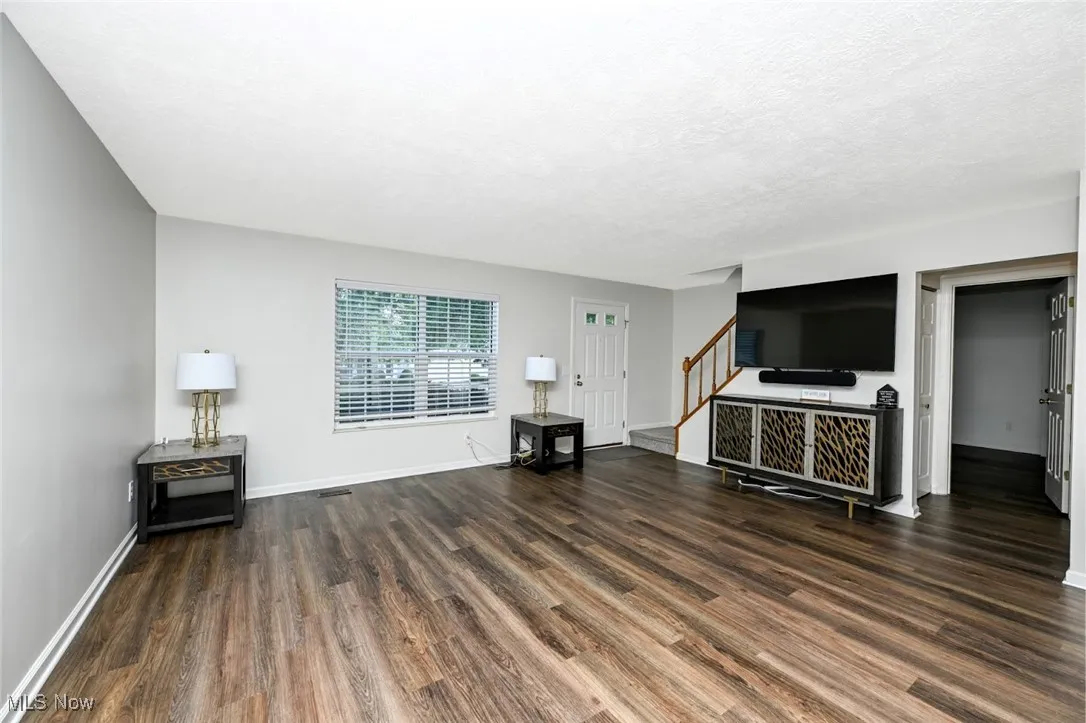 Unfurnished living room with LVP flooring, a textured ceiling, and stairway