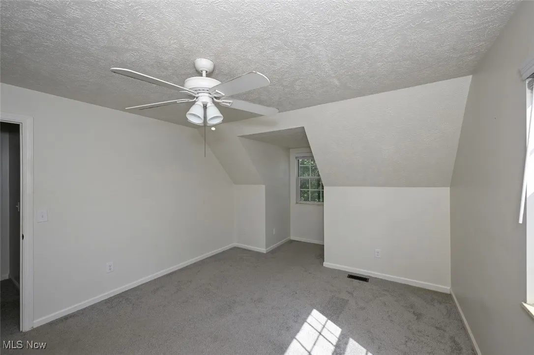 Bedroorm with light carpet, a textured ceiling, ceiling fan, and vaulted ceiling