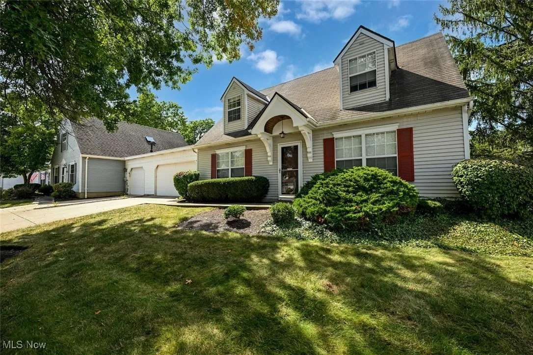 Cape cod home featuring driveway, a garage, a front lawn, and a shingled roof