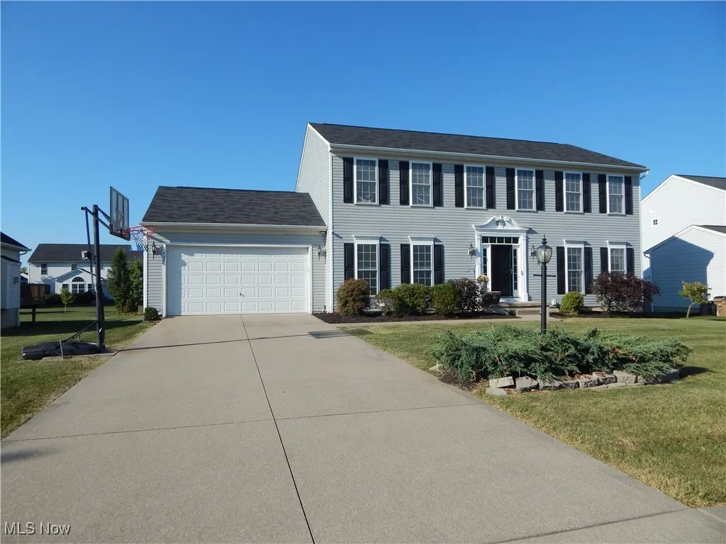 Colonial home featuring a garage, a front yard, and concrete driveway